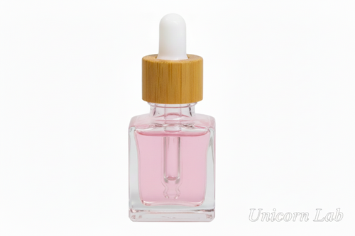 Glass dropper 15ml square bottle with a wooden cap on a white background with pink cuticle oil
