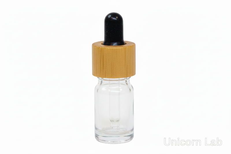 Clear glass  5ml round dropper bottle with a bamboo cap on a white background