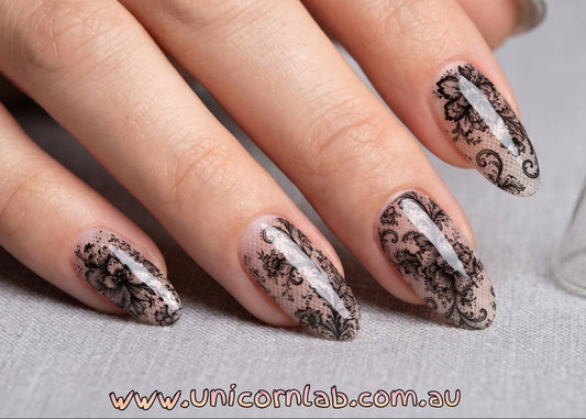 Hand with decorative nails and 'Unicorn Lab' branding on a gray background