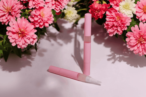Floral Explosion Unicorn Cuticle Oil Pen in front of a bunch of pink flowers.