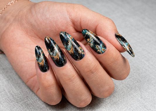 Hand with long, decorated nails on a gray background