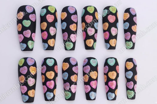 Nail art design with colorful heart shapes on a black background - Unicorn Lab