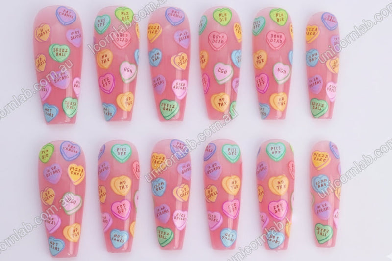 Nail art with colourful heart-shaped candy conversation bubbles on a pink background - Unicorn Lab