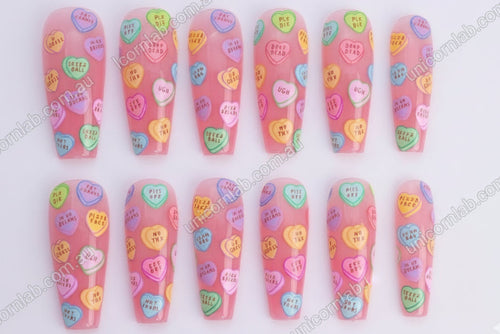 Nail art with colourful heart-shaped candy conversation bubbles on a pink background - Unicorn Lab