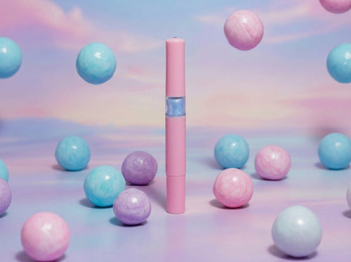 A pink bubblegum scented cuticle oil pen from Unicorn Lab surrounded by colourful gumballs