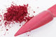 Pink nail powder with scattered powder on a white background