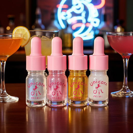 Four bottles of 'Unicorn Cuticle Oil' miniatures on a bar counter with cocktails in the background.