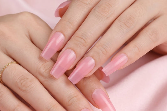 Close-up of hands with pink nail polish on a soft pink background