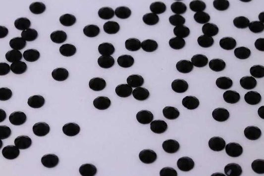 Close-up of Jet SS4 black glass rhinestones on a professional nail art palette.