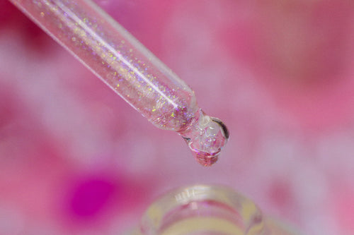 a detailed macro image Eternal Amour Scented Unicorn Cuticle Oil - showing sparkly nail serum in dropper